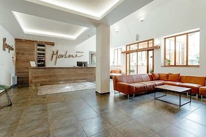 Ein modernes Interieur mit einer Rezeption, einem Ledersofa und einem großen Fenster.