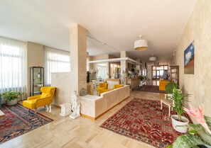 A spacious living area with a yellow armchair, a white sofa, and a patterned rug. - Dei (Fano)