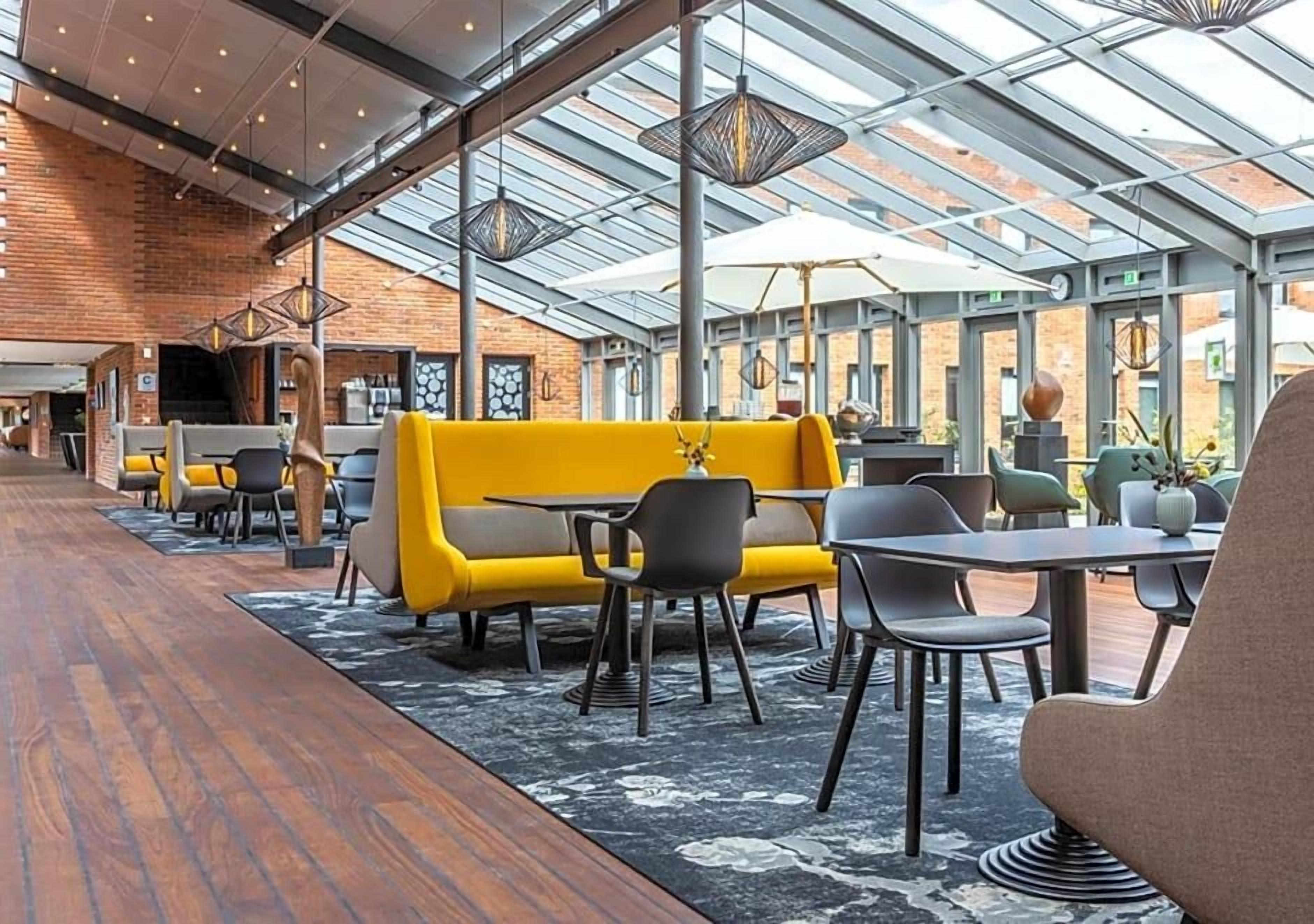 A modern interior with a glass ceiling, yellow seating, and a wooden floor.