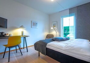 Un dormitorio con cama, escritorio, silla y ventana.
