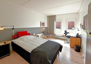 A modern hotel room with a bed, desk, chair, and a view of the outside. - Pharmakon & Conferencecenter (Hillerod)