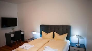 Een hotelkamer met een bed, nachtkastjes, een bureau, een stoel, een televisie en een lamp.