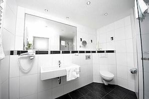Un baño moderno con lavamanos, espejo y retrete blancos.