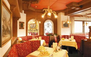 Um restaurante com cabines, lustres e uma decoração de mesa com tema natalino.
