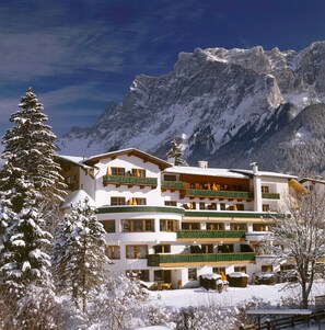 A multi-story hotel with balconies, set against a backdrop of snow-covered mountains. - Schönruh (Ehrwald)