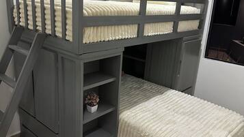 A bunk bed with a ladder, a small shelf with a plant, and a window with blinds.