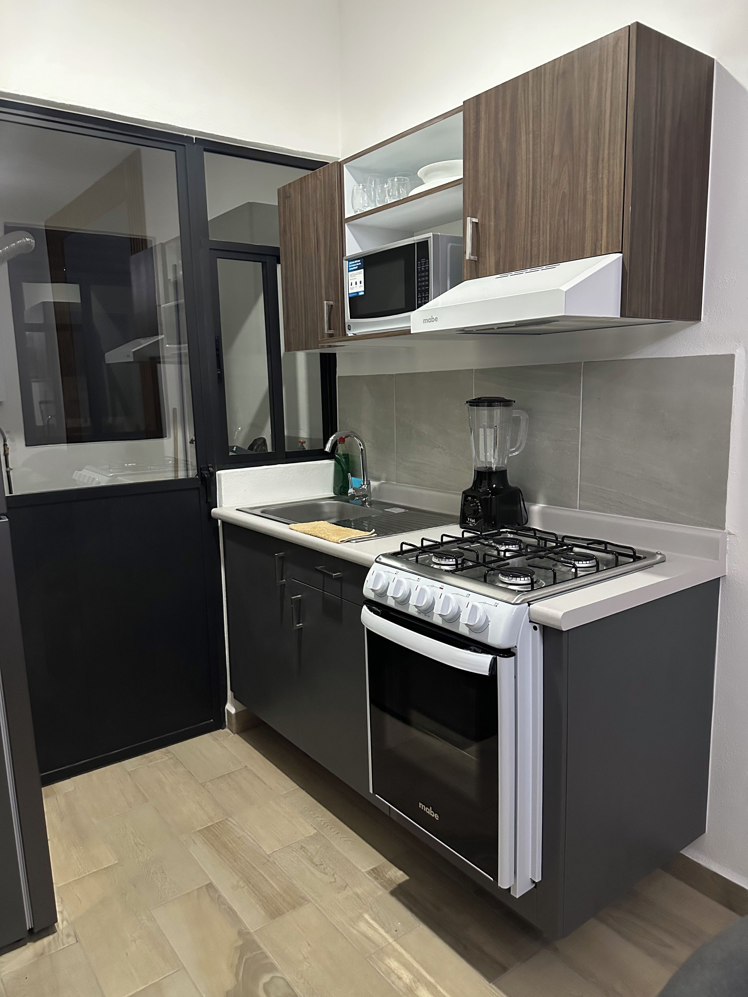 A modern kitchen with a gas stove, oven, microwave, and a blender on the countertop.