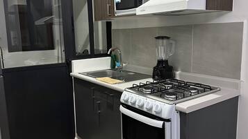 A modern kitchen with a gas stove, oven, microwave, and a blender on the countertop.