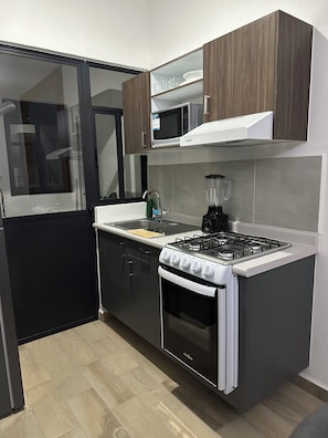 A modern kitchen with a gas stove, oven, microwave, and a blender on the countertop. - Beautiful apartment 5 minutes from GNP Stadium and Palacio Dep. (Ciudad de México)