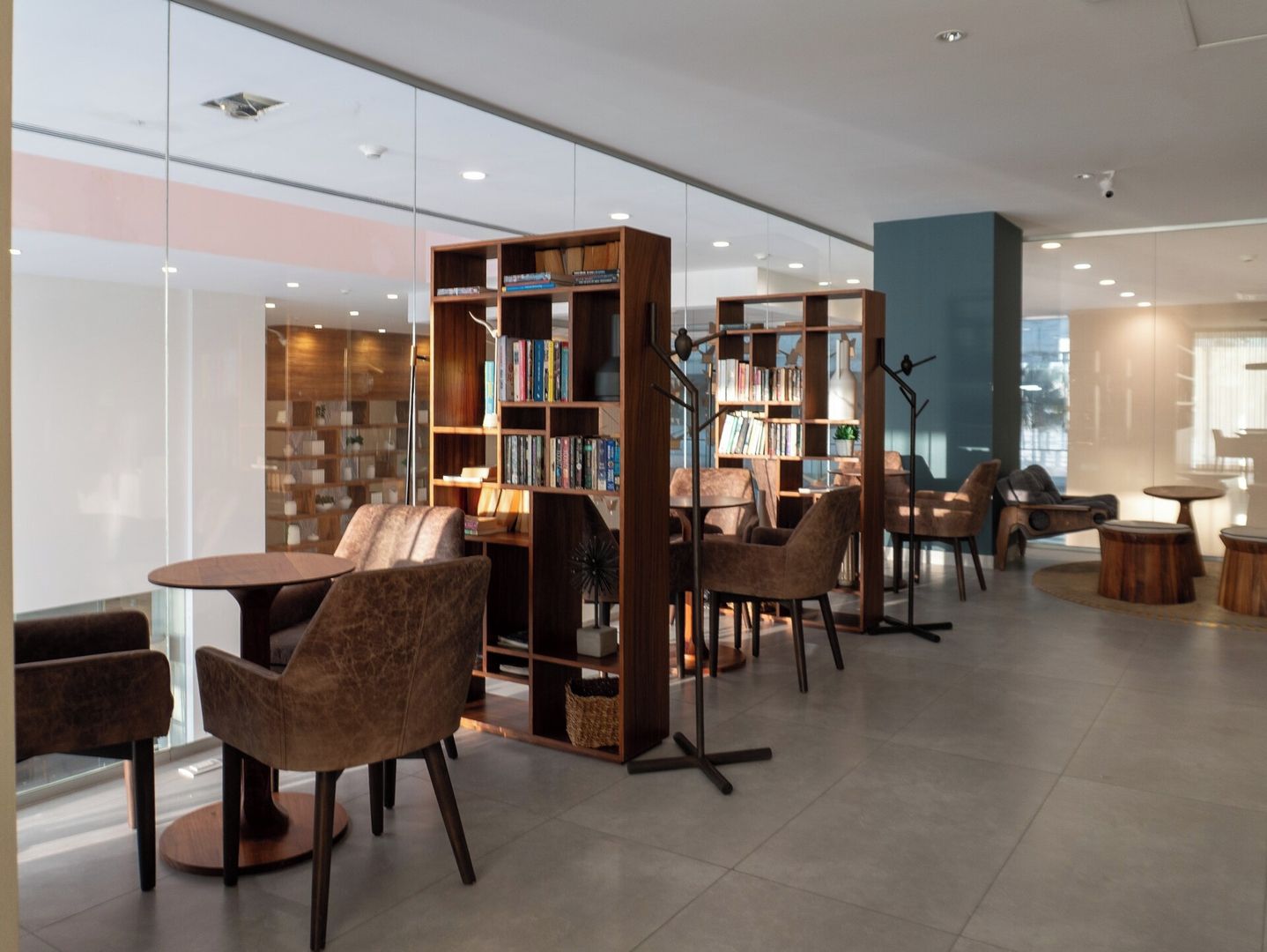 Eine moderne Bibliothek mit Bücherregalen, bequemen Sitzgelegenheiten und einer Glaswand.