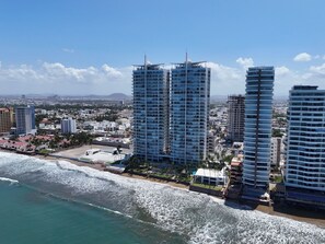 Un paysage urbain côtier avec de hauts immeubles, une plage et un ciel dégagé.