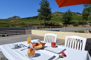 Mesa lista para el desayuno con vista a una carretera y colinas.