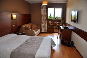 Habitación de hotel con cama, sofá, escritorio y vistas al exterior.