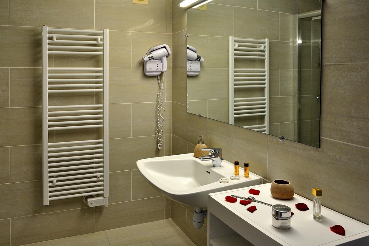 A modern bathroom with a white sink, a mirror, and a towel rack.