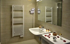 Un baño moderno con un lavabo blanco, un espejo y un perchero para toallas.