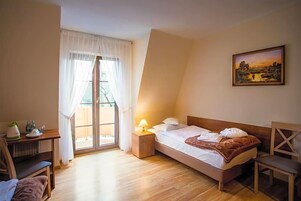 Un dormitorio con cama, escritorio, silla, lámpara y un cuadro en la pared.