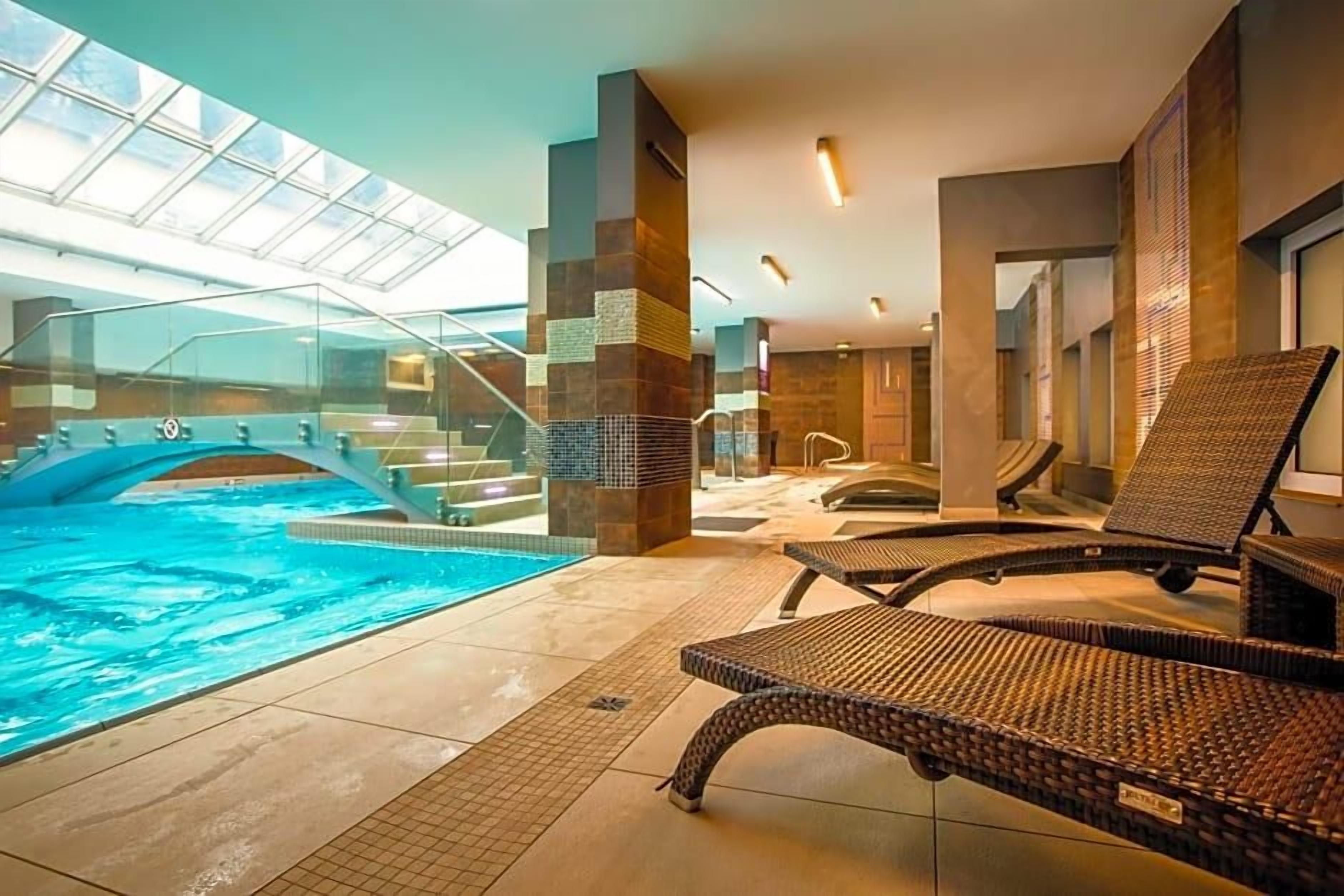 A spa area with a hot tub, lounge chairs, and a glass-enclosed space.