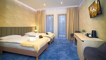 Una habitación de hotel con dos camas, un escritorio, una silla y una televisión en la pared.