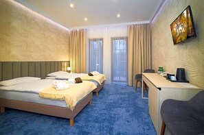 Una habitación de hotel con dos camas, un escritorio, una silla y una televisión en la pared.