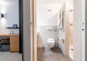 Ein modernes Badezimmer mit Toilette, Handtuchhalter und Duschbereich.