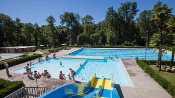 Ein Poolbereich mit mehreren Pools, einer Wasserrutsche und umgebender Bepflanzung.