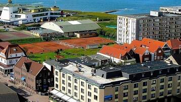 Ein Küstenhotel mit mehreren Gebäuden, einem Parkplatz und Blick auf das Meer.