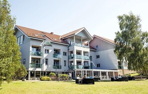 Un hotel de varios pisos con balcones, mobiliario exterior y un patio cubierto.