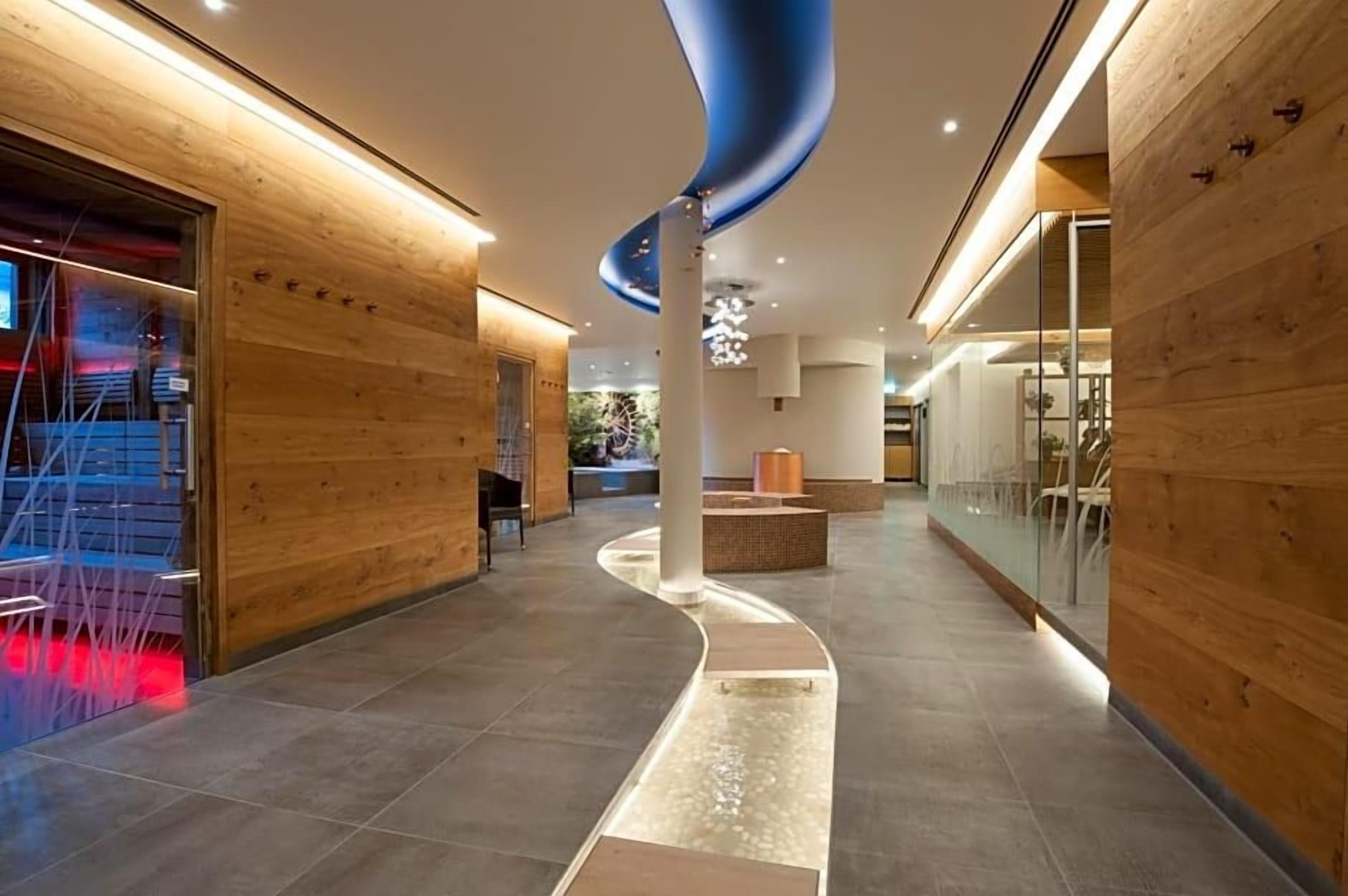 A modern hotel lobby with wooden paneling, a curved ceiling feature, and a seating area.