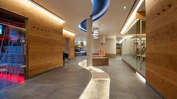 A modern hotel lobby with wooden paneling, a curved ceiling feature, and a seating area.