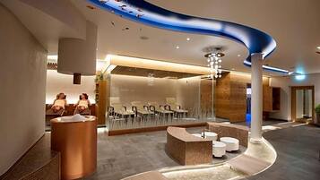 A modern hotel lobby with a curved ceiling, seating areas, and a reception desk.
