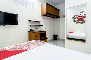 A bedroom with a bed, a desk, a chair, a television, and a wardrobe.