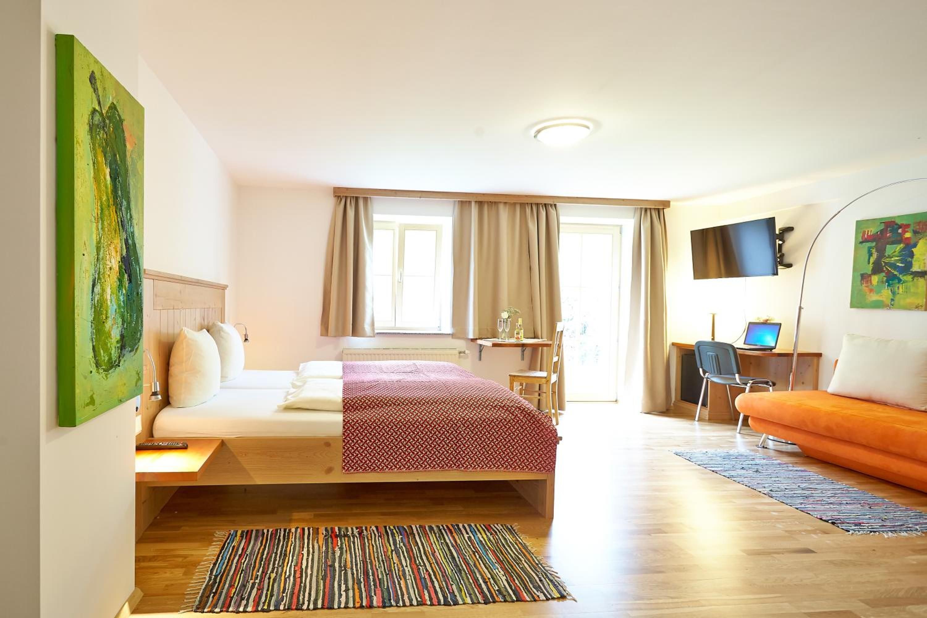 Ein Hotelzimmer mit einem Bett, einem Schreibtisch, einem Fernseher und einem Fenster mit Vorhängen.