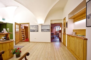 Eine Hotelhalle mit Holzboden, einem Empfangstresen, einer Sitzecke mit Tisch und Stühlen und gerahmten Bildern an den Wänden.