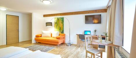Una habitación de hotel con una cama, un escritorio con computadora, un sofá y un cuadro en la pared.