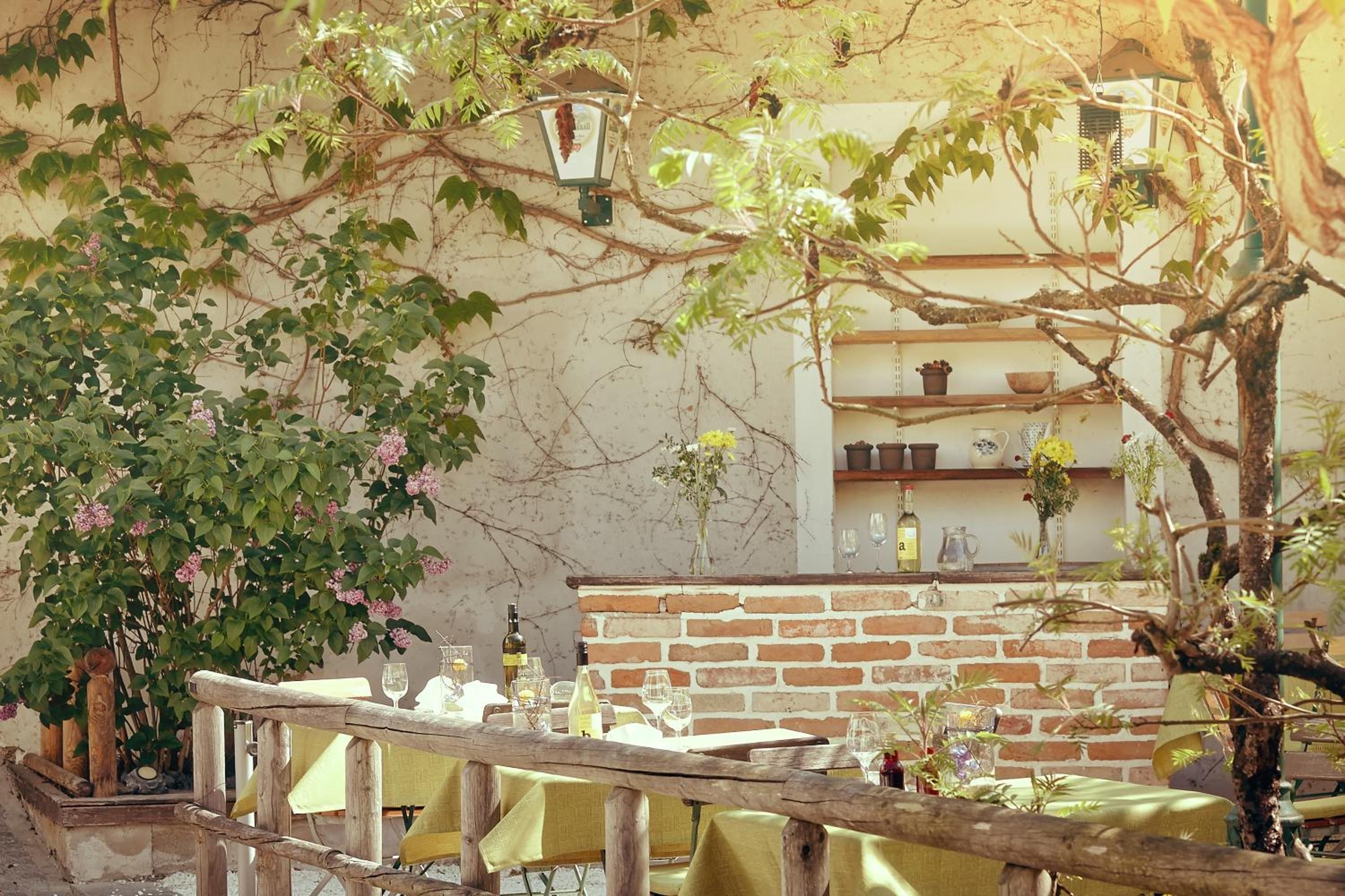 An outdoor dining area with a brick wall, wooden table, and chairs.