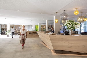 Un moderno vestíbulo de hotel con mostrador de recepción, zona de estar y un amplio ventanal que proporciona luz natural.