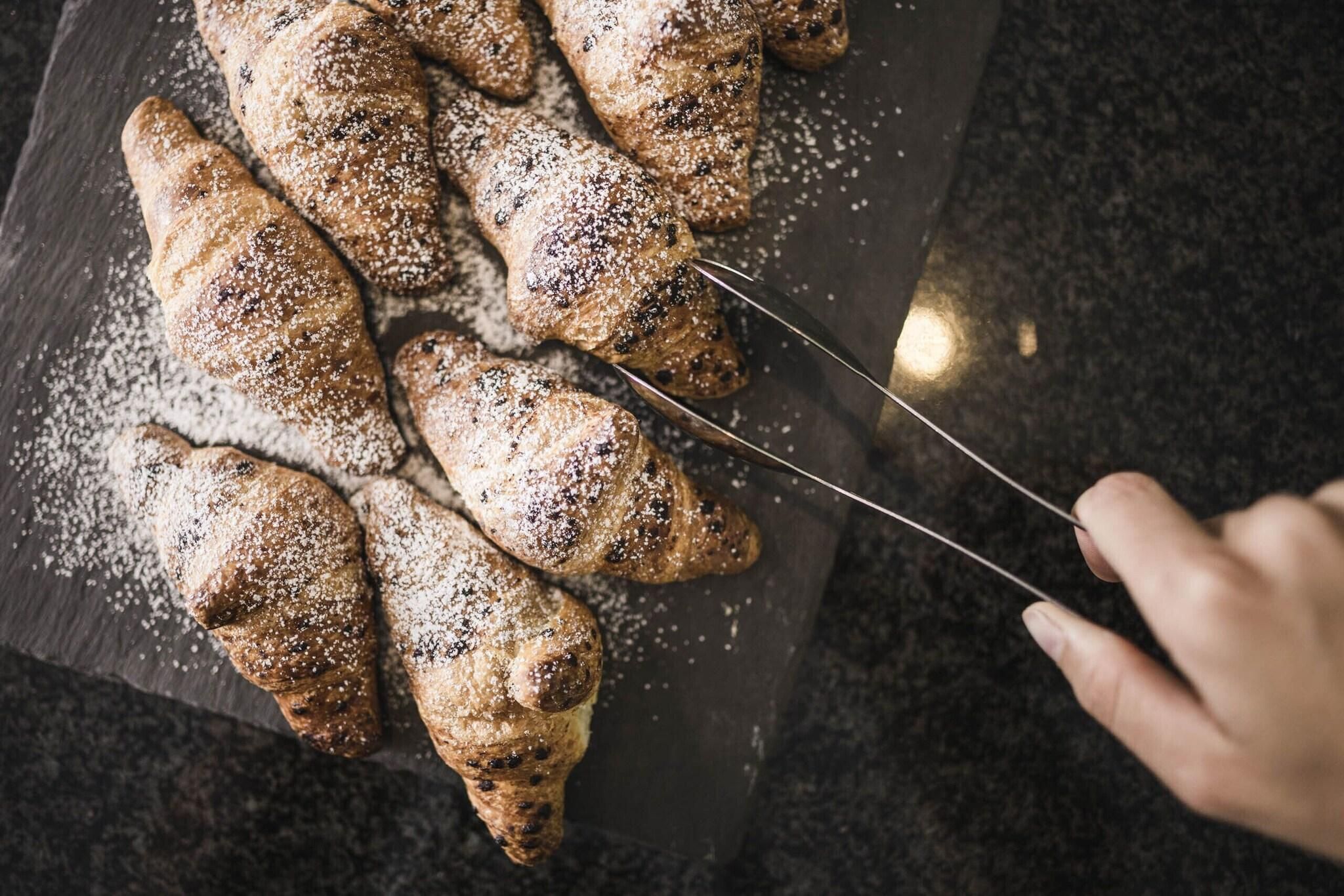 A person cutting a pastry with a knife.