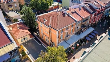 A multi-story building with a red-tiled roof, a central courtyard, and a street-facing facade with outdoor seating.