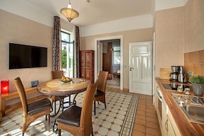 A dining area with a round table, wicker chairs, and a flat-screen TV. - Recknitztal Hotel (Marlow)
