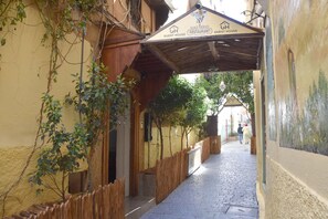A narrow alleyway with a wooden fence, a sign for a guest house and restaurant, and a building entrance. - Riad Verus (Fes)
