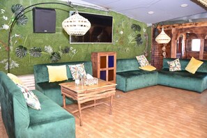 A room with green upholstered sofas, a wooden coffee table, and a large window. - Riad Verus (Fes)