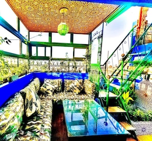 A room with a patterned ceiling, a green staircase, and a blue sofa with patterned cushions. - Riad Verus (Fes)