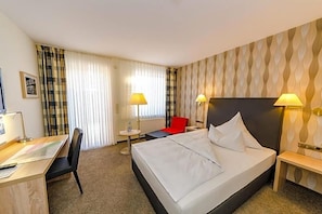 A hotel room with a bed, desk, chair, and two bedside lamps. - Quellenhof (Salzgitter)