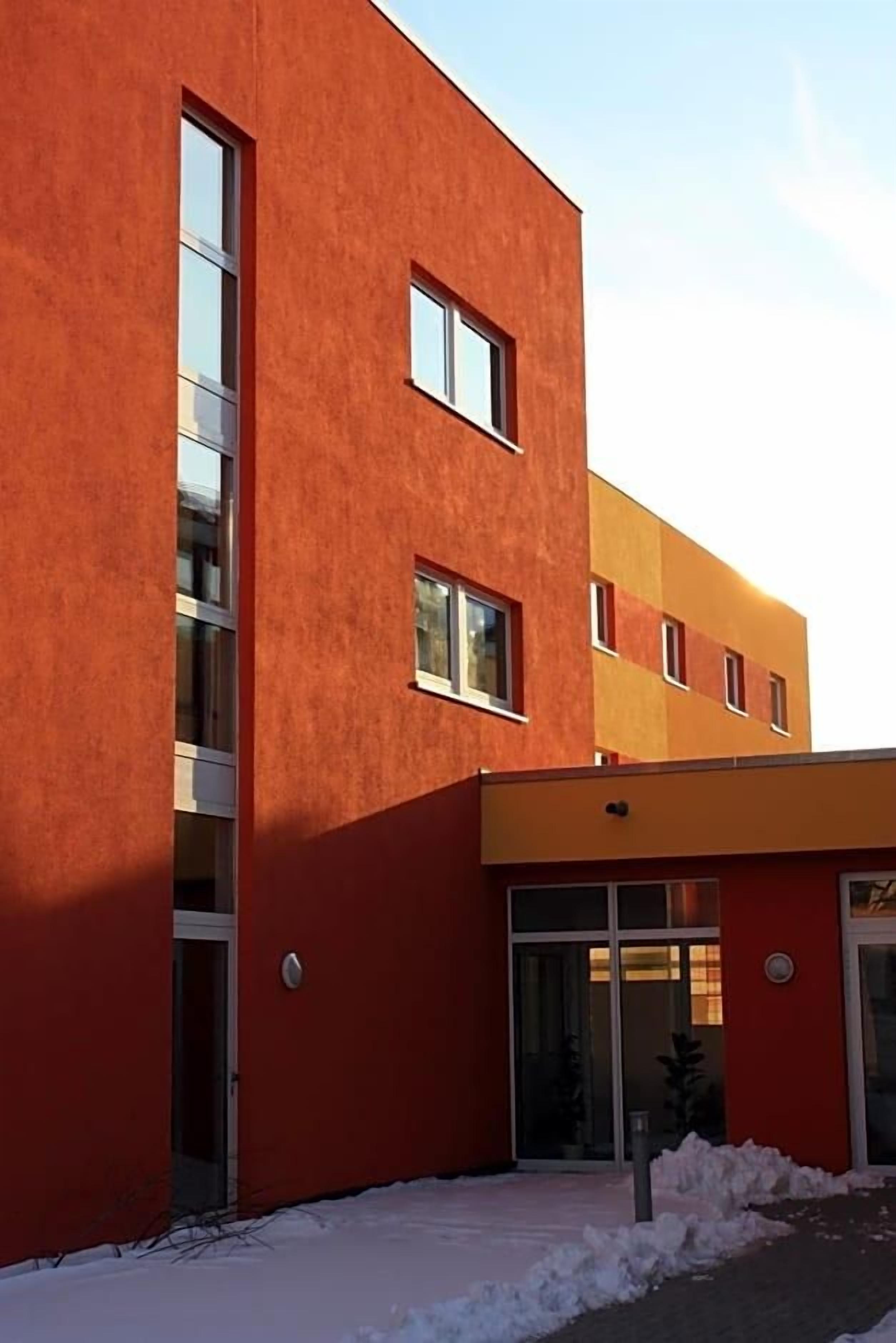 A modern building with a red facade and large windows.