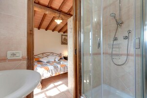 Un baño con ducha, cama y lavabo.