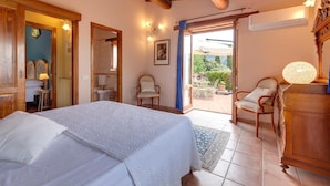 Une chambre à coucher avec un lit, une armoire en bois, une chaise et une vue sur l’extérieur.