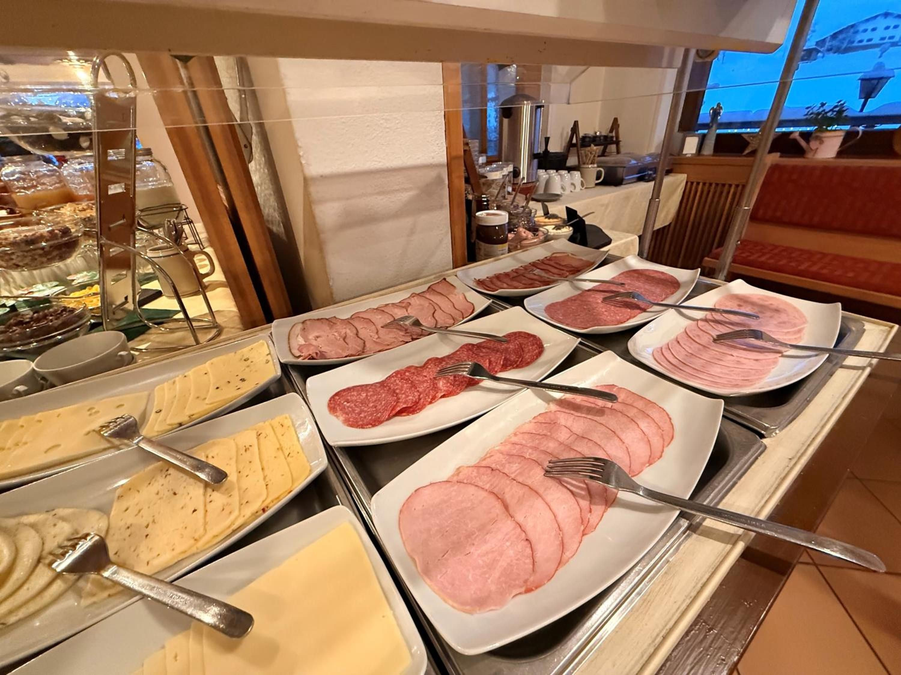 Un bufé con diversas opciones de comida, incluyendo fiambres y quesos.