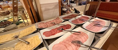 Un bufé con diversas opciones de comida, incluyendo fiambres y quesos.