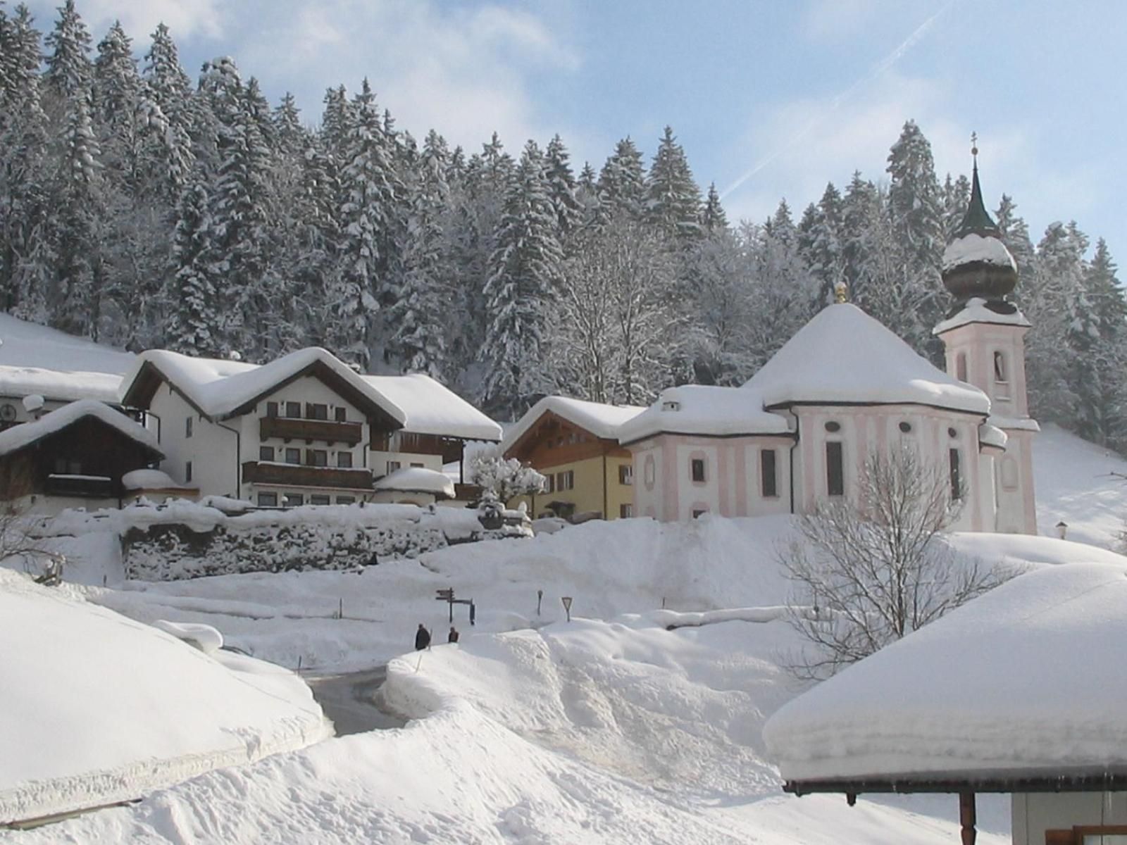 Ein schneebedecktes Dorf mit traditionellen Gebäuden und einer Kirche mit Kuppel.