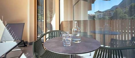 A balcony with a round table, two chairs, a bottle, and glasses.